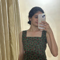 Woman taking a mirror selfie wearing a green dress with a floral pattern.